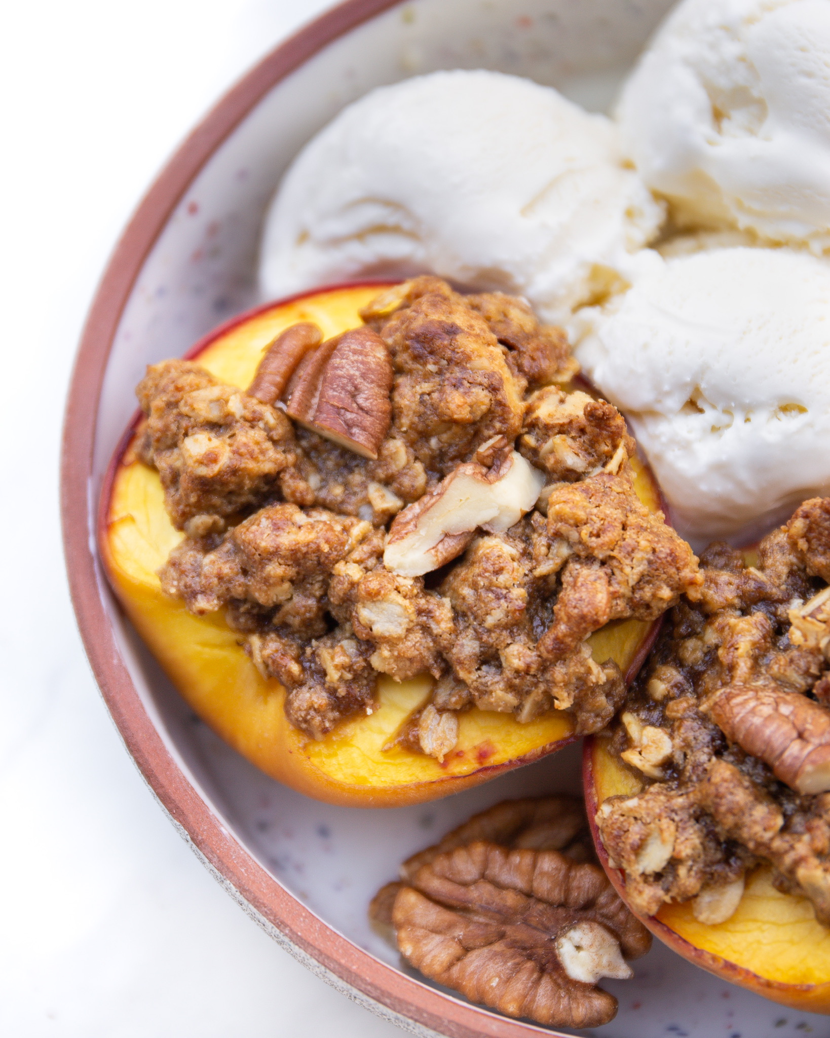 personal pecan peach crumble in bowl with vanilla ice cream