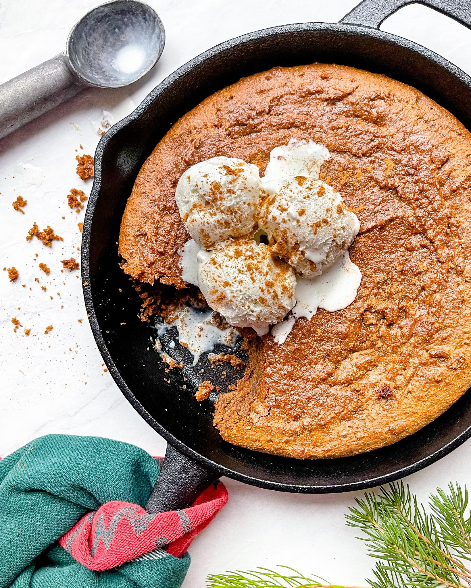 grain free gingerbread cookie skillet in cast iron with ice cream and ice cream spoon